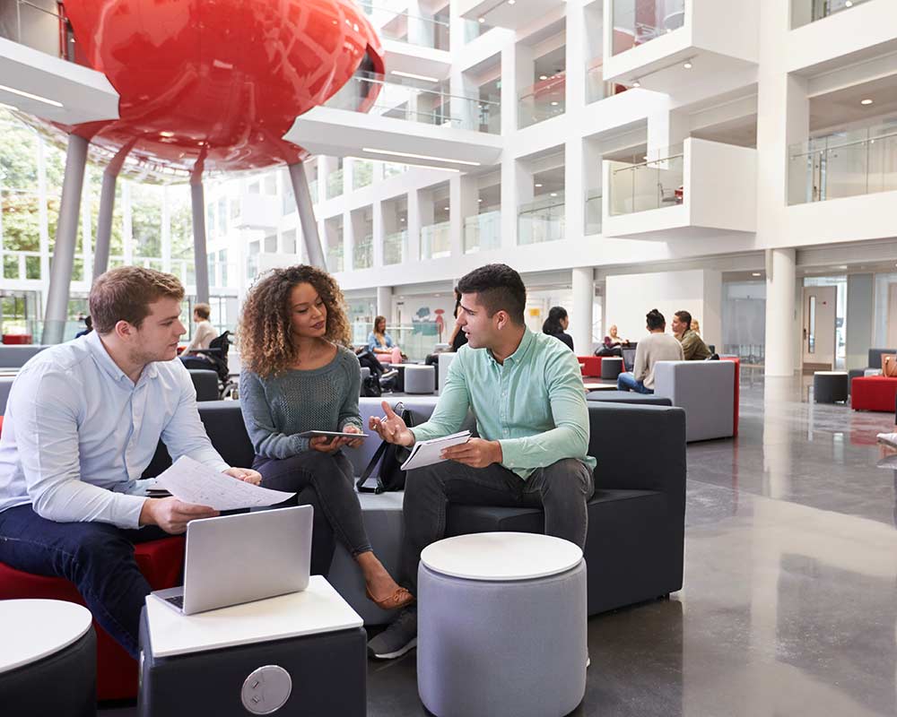 A small group of MBA students chat in an open foyer